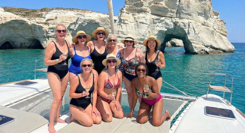 A group of women travellers pose for a photo on the tramp of a large catamaran