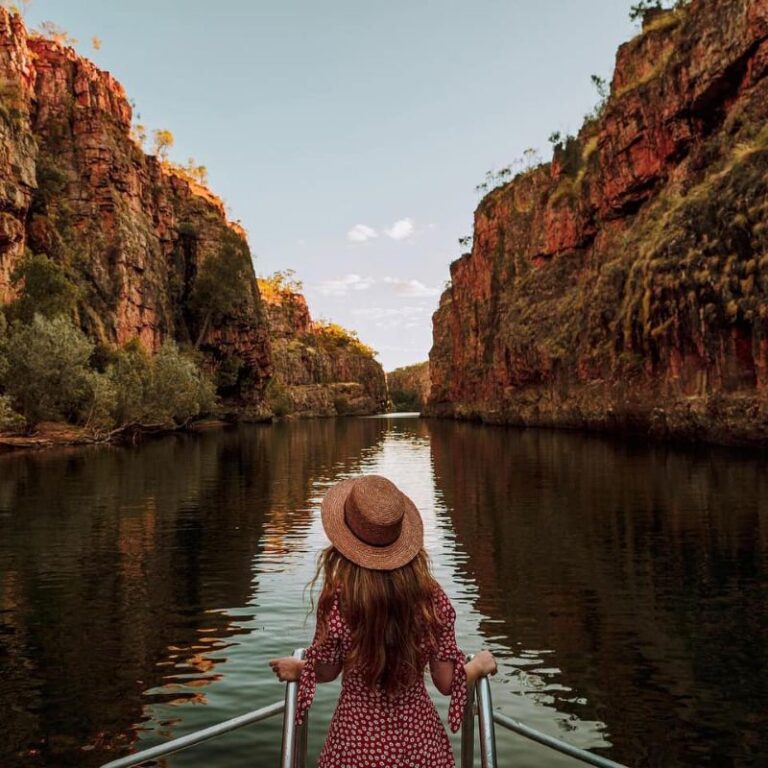 A women stands at the bow of a boat cruising through a spectacular gorge